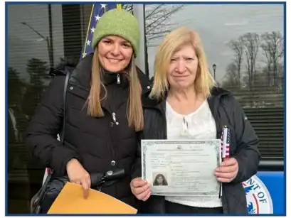 Two women holding immigration documents outside the law office.